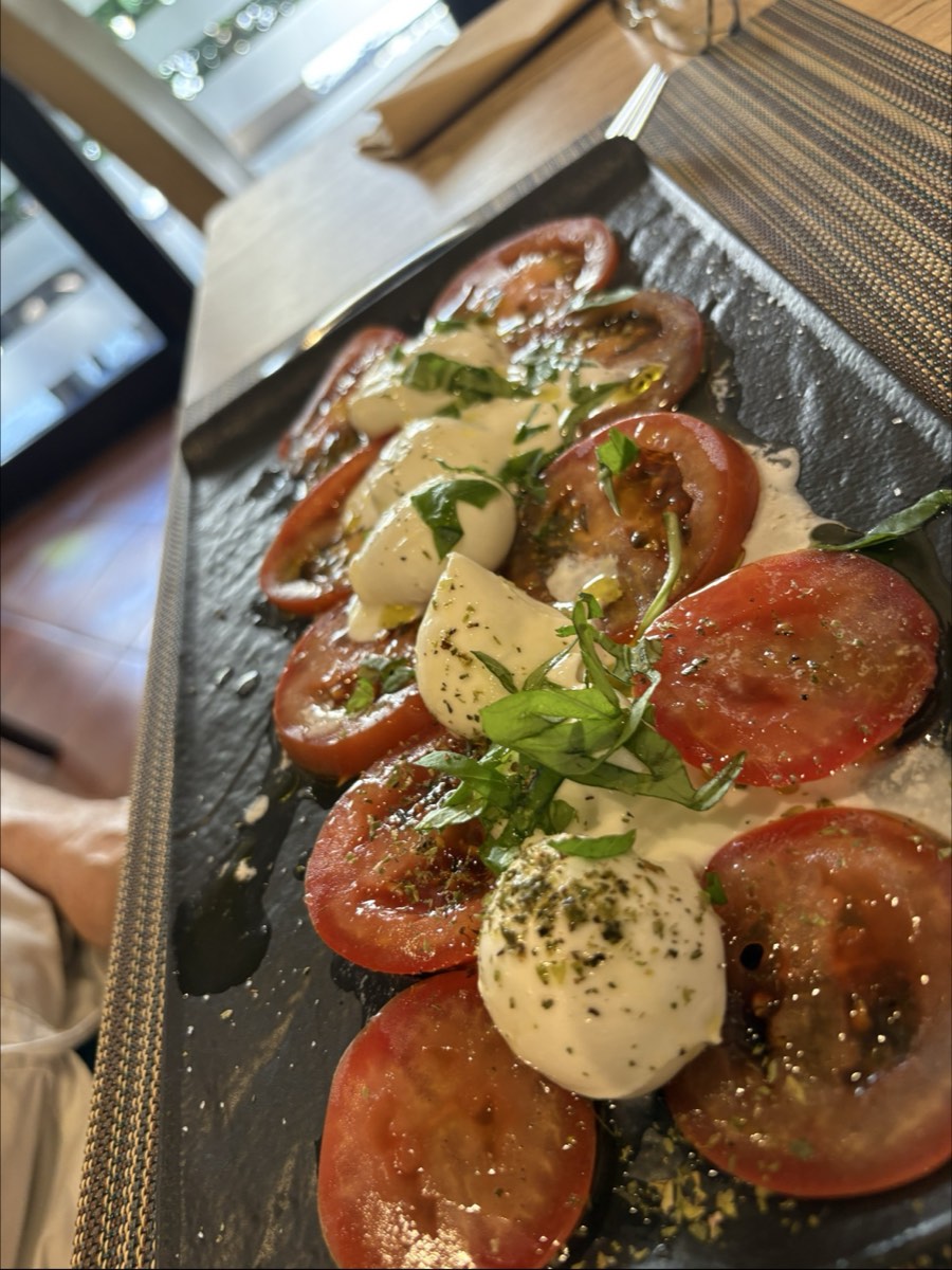 Caprese di pomodori, mozzarella e basilico servita su ardesia